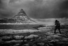 Kirkjufell
Fotós dacol az orkán erejű széllel és esővel az észak izlandi jellegzetes, boszorkánysüveget formázó Kirkjufell hegy előterében.